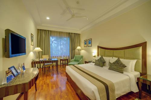 Habitación de hotel con cama grande y escritorio. en Muse Sarovar Portico Nehru Place, en Nueva Delhi