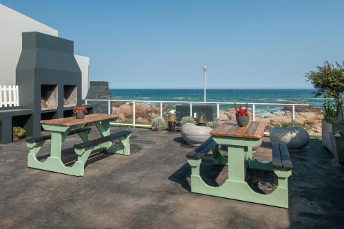 eine Terrasse mit zwei Picknicktischen und dem Meer in der Unterkunft Albatross Accommodation in Lambertʼs Bay