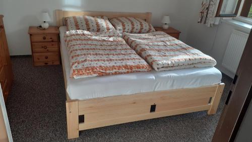 een bed met een houten frame en kussens erop bij Apartmán Danuška Harrachov in Harrachov