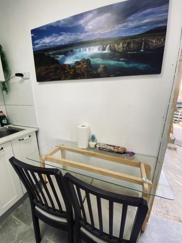 a glass table with two chairs and a painting on the wall at Yogo Place in Nahariyya in Nahariyya
