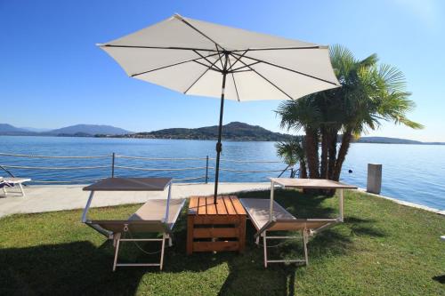 two chairs and an umbrella next to the water at Resort Antico Verbano in Meina