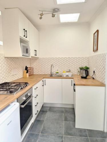 eine Küche mit weißen Schränken und Arbeitsflächen aus Holz in der Unterkunft Sunlight Cottage in Kapstadt