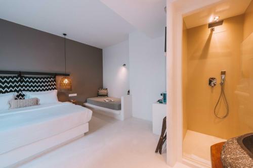 a bedroom with a large white bed and a bathroom at My Mykonos Hotel in Mýkonos City