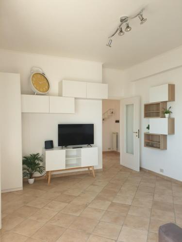un soggiorno con TV a schermo piatto su una parete bianca di IL MARE DI ROMA APARTMENT a Lido di Ostia