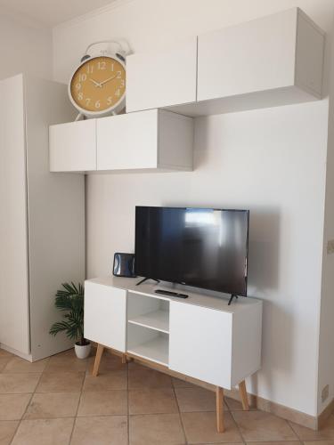 un centro di intrattenimento bianco con TV e orologio di IL MARE DI ROMA APARTMENT a Lido di Ostia