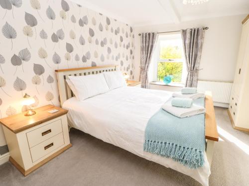 a bedroom with a bed and a table and a window at Glenridding Cottage in Warcop