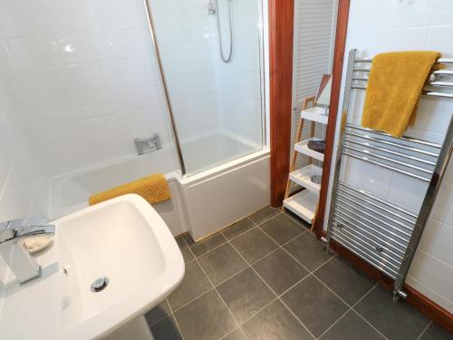 a bathroom with a white sink and a shower at Glenridding Cottage in Warcop