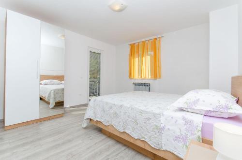 biała sypialnia z łóżkiem i lustrem w obiekcie Apartments Marinko w Makarskiej