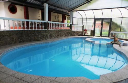 a large blue swimming pool in a building at Hosteria Agoyan in Baños