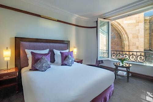 a bedroom with a large white bed and a window at Hôtel Pont Royal Paris in Paris