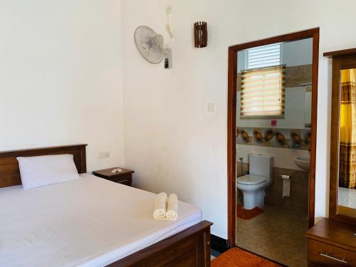 a bedroom with a bed and a bathroom with a toilet at The Kingslayer Resort in Negombo
