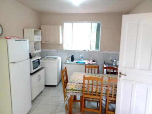 uma cozinha com uma mesa e cadeiras e um frigorífico branco em Casa a 40 metros da praia em Governador Celso Ramos