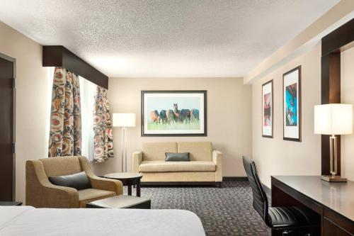 a hotel room with a bed and a desk and chairs at Holiday Inn Louisville East - Hurstbourne by IHG in Louisville