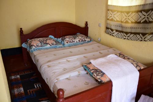 ein Schlafzimmer mit einem Bett mit einem Holzrahmen in der Unterkunft NYUNGWE VILLAGE in Kitabi