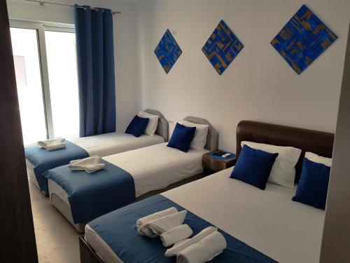 three beds in a room with blue and white at Villa Alba Apartments in Dobra Voda