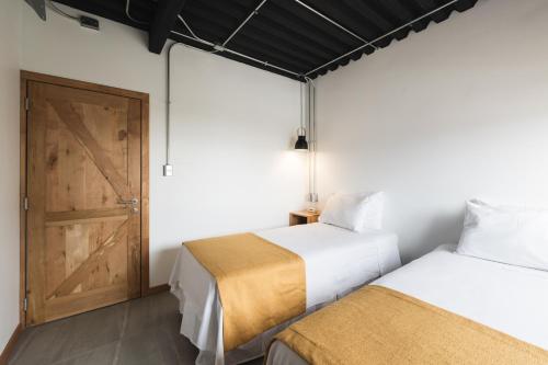 two beds in a room with a door at Hotel Big Sur in Puerto Natales