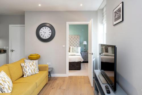 a living room with a couch and a clock on the wall at The Hastings, Lower Borough Walls in Bath