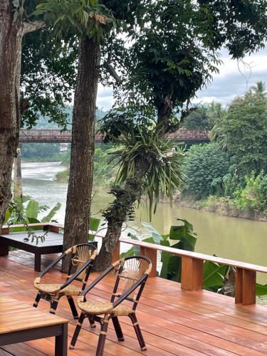 two chairs on a deck with a view of a river at Moonlight Champa Riverview in Luang Prabang