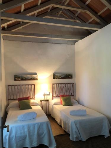 two beds in a room with white walls and wooden ceilings at Casa de la vega in Almodóvar del Río