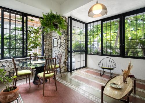 um quarto com uma mesa, cadeiras e janelas em La Botanica Hotel em San Juan