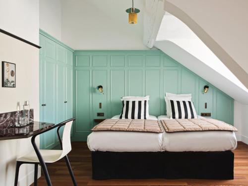 een slaapkamer met een bed en een tafel en stoel bij New Hotel Lafayette in Parijs