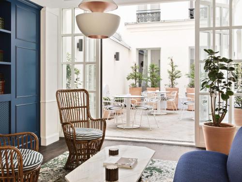 ein Wohnzimmer mit Stühlen und Tischen und ein Zimmer mit blauen Wänden in der Unterkunft New Hotel Lafayette in Paris