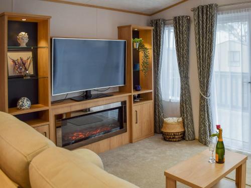 een woonkamer met een televisie en een open haard bij Bruar Lodge in Cameron