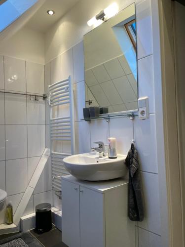 Baño blanco con lavabo y espejo en Ferienwohnung Lüttje Hörn, en Emden