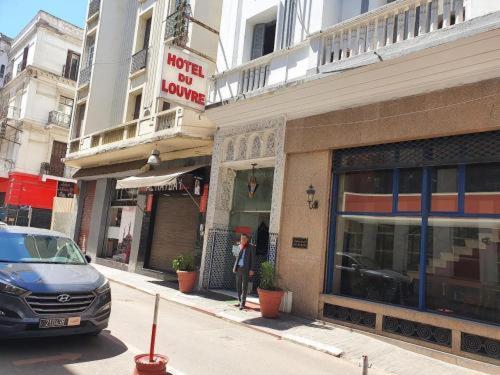 a man standing outside of a store on a city street at HOTEL DU LOUVRE in Casablanca