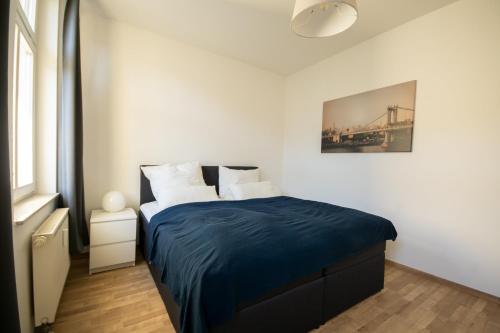 ein Schlafzimmer mit einem Bett mit einer blauen Decke in der Unterkunft Wunderschön gepflegter Altbau, Aufzug in Chemnitz