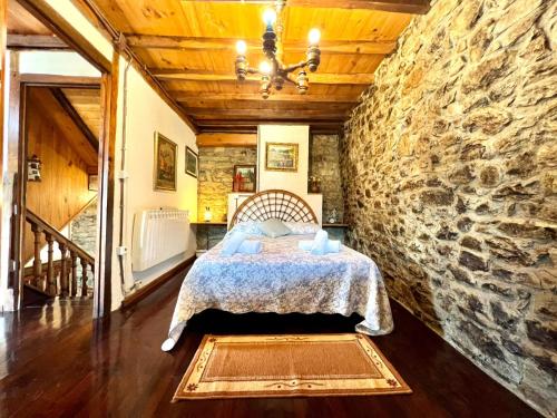 a bedroom with a bed in a stone wall at Casa con 2 dormitorios, chimenea, jardin y vista a la montaña in Campomanes