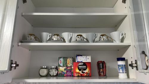 a shelf with cups and other items on it at Luxurious apartment with 3 rooms and 2 bathrooms in Corabia in Corabia