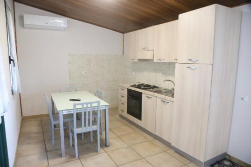uma cozinha com armários brancos e uma mesa e cadeiras em Hostaria delle Memorie em Curinga