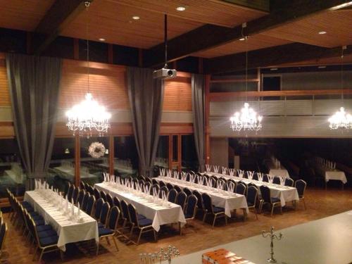 a banquet hall with white tables and chairs and chandeliers at Hotelli Viikinhovi in Keuruu