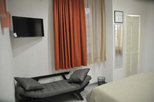a bedroom with a chair and a television on a wall at Casa Monì in Naples