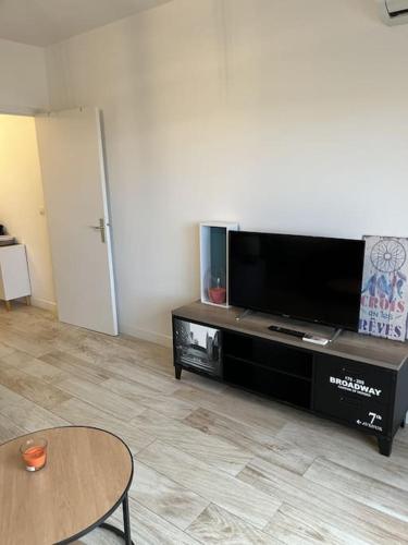 un salon avec une télévision à écran plat et une table dans l'établissement SUPERBE APPARTEMENT FACE AUX ILES SANGUINAIRES, à Ajaccio