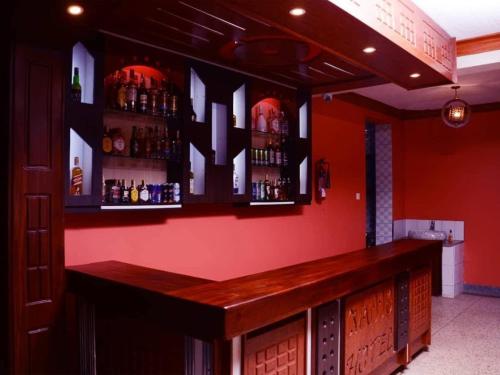 a bar with a red wall with alcohol bottles at Mujjo Hotel Kajjansi in Kampala