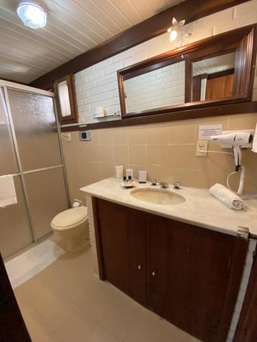 a bathroom with a sink and a toilet and a shower at Apartamento Foss in Gramado