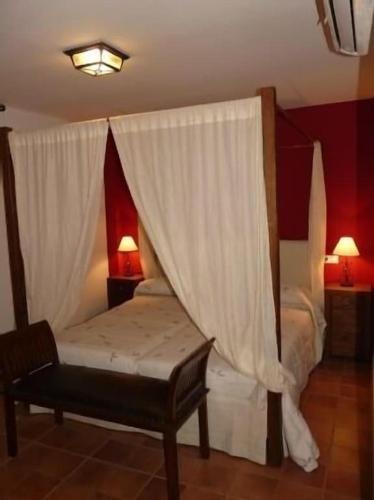 a bedroom with a bed with a canopy and a chair at Apartamentos en sierra de gata ALMA in Villamiel