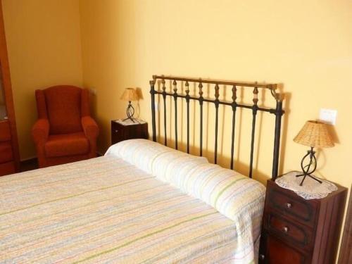a bedroom with a bed and an orange chair at Apartamentos en sierra de gata ALMA in Villamiel