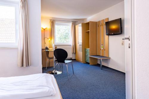 a room with a bed and a desk and a tv at Hotel zur Börse in Hameln