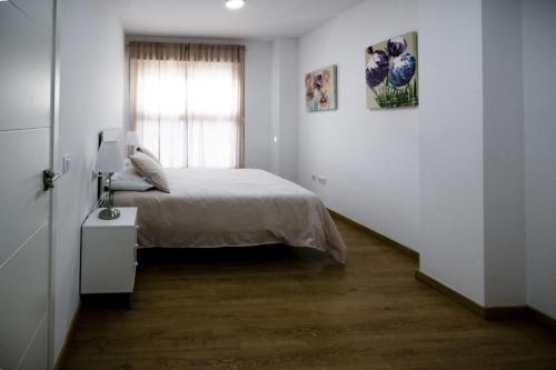 a white bedroom with a bed and a window at Apartamento San Juan in El Puerto de Santa María