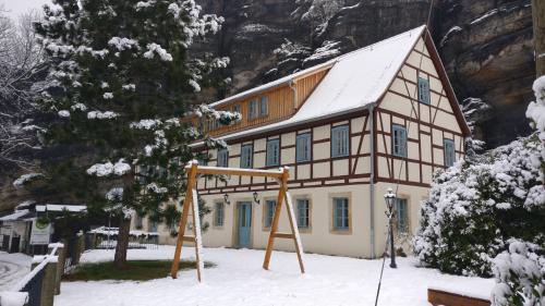a house in the snow with a swing at Ferienwohnungen Felsenkeller Bielatal in Bielatal