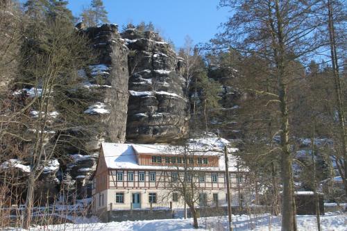 a building in front of a mountain with snow at Ferienwohnungen Felsenkeller Bielatal in Bielatal
