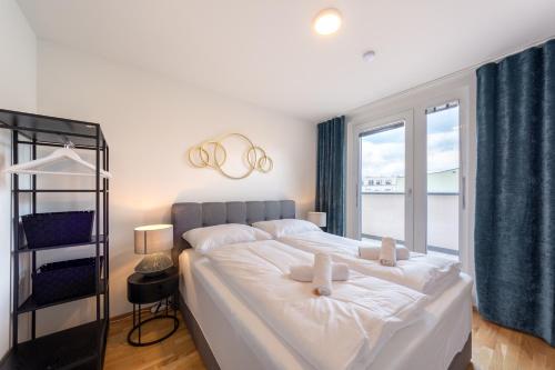 a bedroom with a large white bed with a window at Modernes Stadtapartment mit Terrasse in Vienna