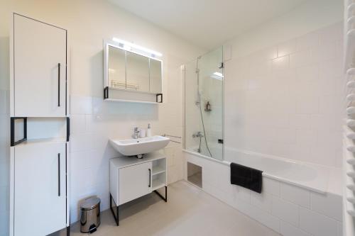 a white bathroom with a sink and a shower at Modernes Stadtapartment mit Terrasse in Vienna