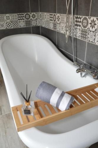 a white bath tub with a wooden shelf in a bathroom at MAS DE LA FORGE NOGUIER in Vergèze