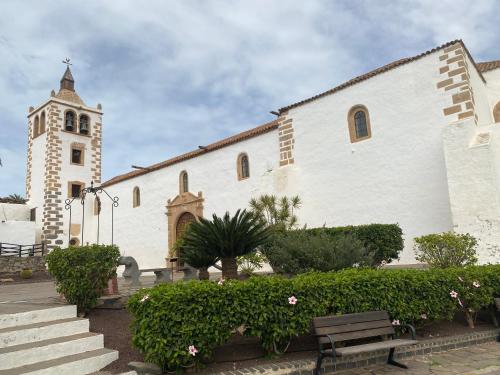a white church with a clock tower and a bench at Apartamento tranquilo Sun Beach in Caleta De Fuste
