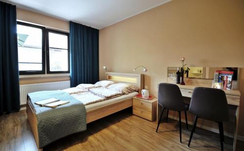 - une chambre avec un lit et un bureau avec des chaises dans l'établissement BALTIC VIBES - pokoje gościnne, à Kołobrzeg