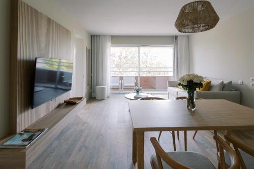 a living room with a table and a tv at The Editory By The Sea Troia Comporta Hotel in Troia